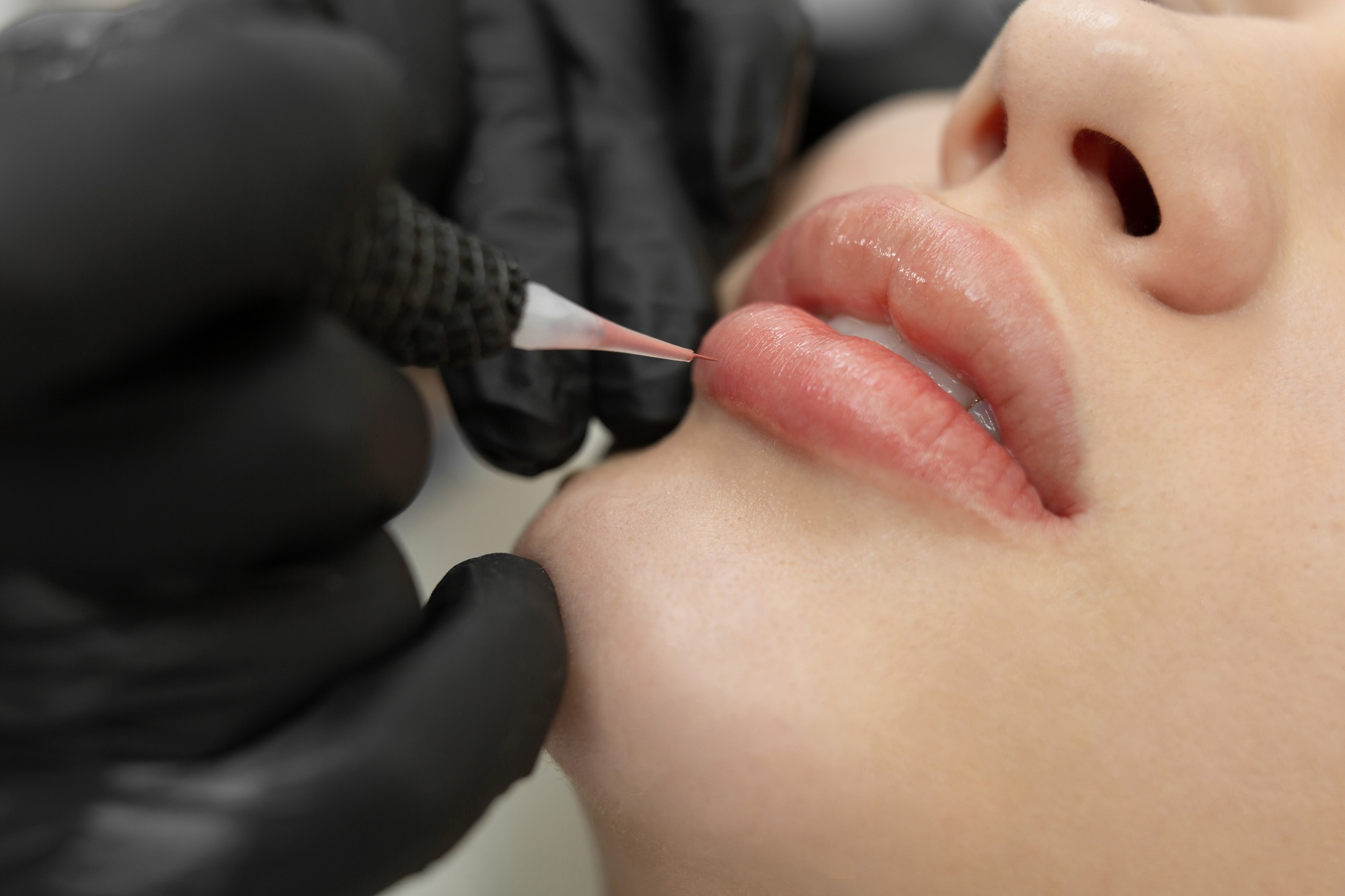 Close-up of the permanent makeup procedure. Lip makeup in the cosmetologist's salon